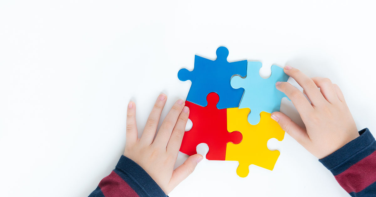 Top view, hands of an autistic child play colorful puzzle which